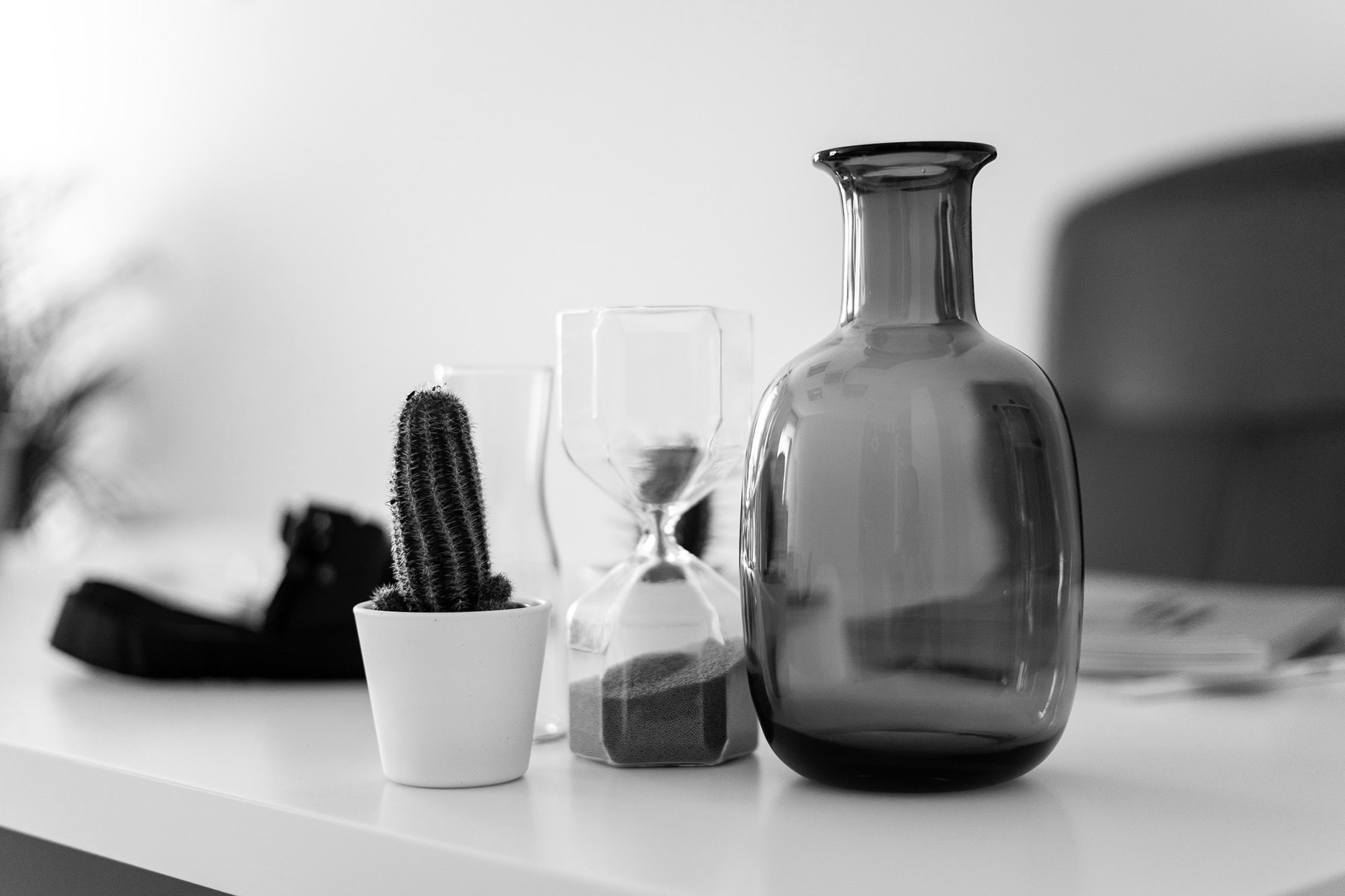 Detalle de mesa de trabajo en A Coruña con cactus, reloj de arena y botella decorativa.