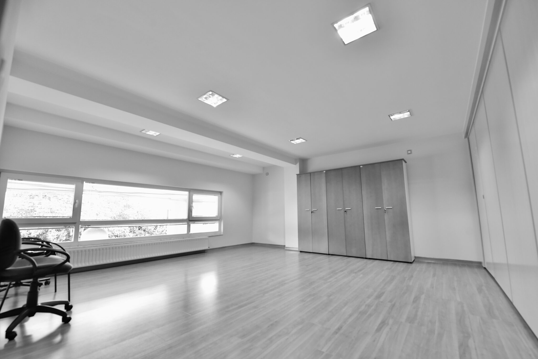 Sala amplia de Lugo con ventana horizontal, armarios empotrados y zona despejada para trabajo flexible.